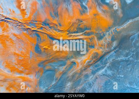 Une vue aérienne fascinante d'un paysage naturel transformé en toile abstraite multicolore, révélant des motifs complexes et des bandes audacieuses d'oran Banque D'Images