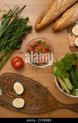 Une vue de haut en bas des ingrédients frais pour une salade, y compris les herbes, la salade de tomates, les œufs durs, la laitue, baguettes, et oignons verts, magnifiquement arrang Banque D'Images