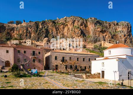 Maisons traditionnelles en pierre et une église orthodoxe à Chryssafitissa Square, Monemvasia, Grèce. Situé contre une falaise rocheuse spectaculaire, cette ville médiévale e Banque D'Images