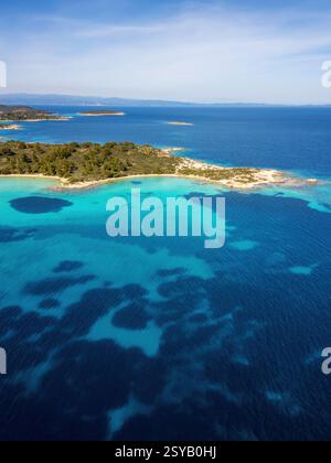 Vue aérienne de l'île de Diaporos et de la plage de Karydi, en Grèce, avec des eaux turquoises vives, des forêts verdoyantes et des rives rocheuses. Une Méditerranée à couper le souffle c Banque D'Images