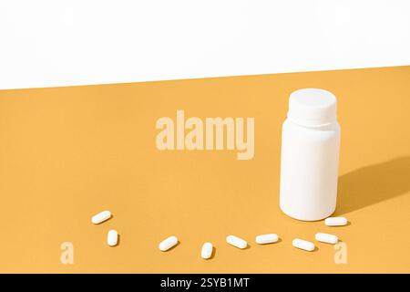Composition minimaliste avec une bouteille de pilules blanche et des pilules dispersées sur une surface jaune vif. Imagerie idéale pour les produits pharmaceutiques ou de santé Banque D'Images