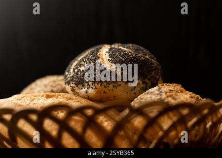 Pain fraîchement cuit avec des graines de pavot. Assortiment de pâtisseries fraîches. Pain dans un panier en osier sur la table. Photo de haute qualité Banque D'Images
