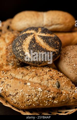 Pain fraîchement cuit avec des graines de pavot. Assortiment de pâtisseries fraîches. Pain dans un panier en osier sur la table. Photo de haute qualité Banque D'Images
