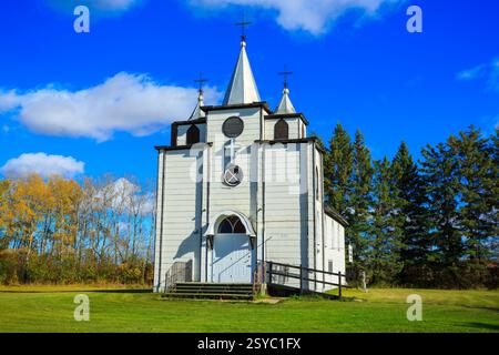 Église blanche avec un clocher et une croix sur le dessus. L'église est entourée d'arbres Banque D'Images