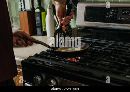 plan large d'un homme cuisant des œufs pour le petit déjeuner sur sa cuisinière à gaz Banque D'Images