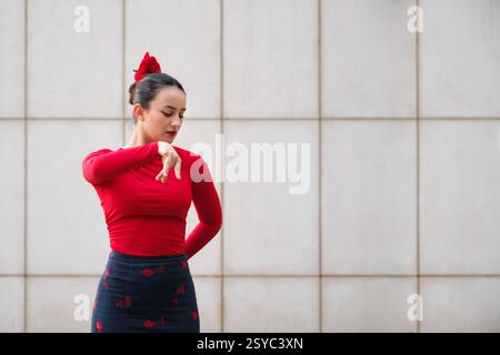 Danseuse de flamenco jouant avec des vêtements rouges devant un mur Banque D'Images
