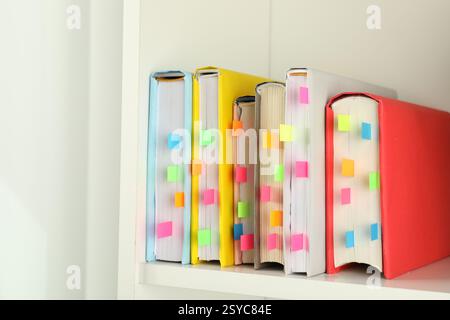 Livres avec des onglets colorés sur étagère blanche à l'intérieur Banque D'Images