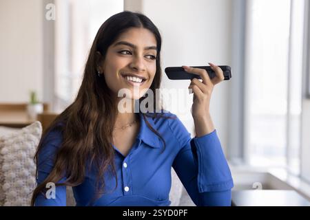 Belle femme indienne tenant un smartphone, écoutant un message vocal Banque D'Images