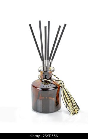 Les bâtonnets noirs de désodorisant sont insérés dans une bouteille de parfum en verre brun. Banque D'Images