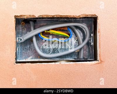 Prise électrique dans un trou coupé dans des plaques de plâtre sur les murs d'une extension de maison. Personne. Banque D'Images