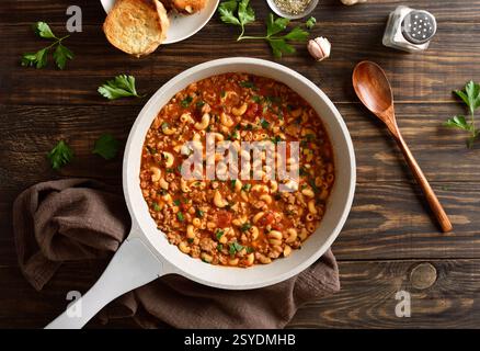 Macaronis cuits avec du bœuf haché, des légumes et des pâtes dans une sauce tomate dans une casserole de cuisson sur fond de bois. Vue de dessus, pose à plat Banque D'Images