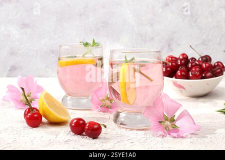 Thé glacé cerise ou cocktail de menthe et citron, une recette rafraîchissante de boisson estivale. Verre avec limonade aux fruits de pomme sur table en béton léger, régime de désintoxication et Banque D'Images