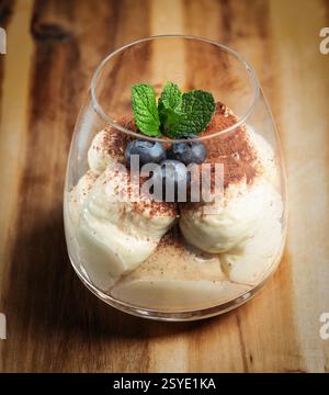Dessert tiramisu italien classique servi dans un verre avec de la menthe fraîche et des myrtilles. Banque D'Images