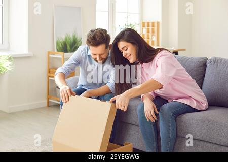Couple regarde joyeusement et avec attente à l'intérieur de la boîte en carton ouverte, regardant un nouvel achat ou un cadeau. Banque D'Images