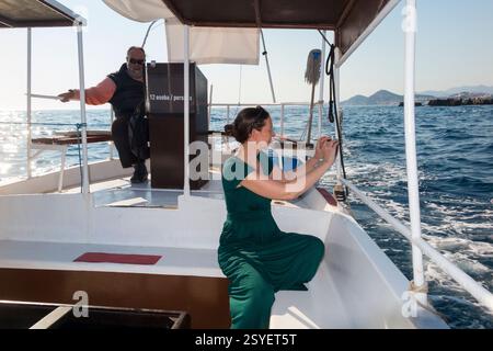 Femme prenant des vacances snap sur le voyage en famille en bateau partant de la vieille ville Port de Dubrovnik, Croatie, en bateau touristique à fond de verre donnant aux touristes des voyages autour de l'île de Lokrum et de la mer Adriatique côtière. Journée ensoleillée avec ciel bleu et soleil. Skipper / capitaine regarde. (138) Banque D'Images