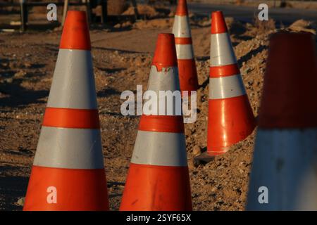Les cônes réfléchissants orange avertissent des dangers sur un chantier de construction. Banque D'Images