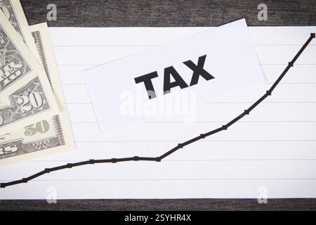 Inscription taxe, billets de banque en dollars et graphique en hausse montrant les augmentations de taxes. Calcul et paiement de l'impôt. Fond en bois Banque D'Images