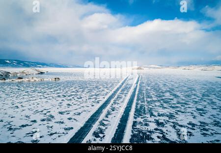 Aérienne de route d'hiver à travers la surface gelée du lac Baïkal sous un ciel bleu Banque D'Images