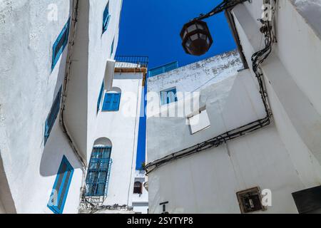 Vue vers le haut d'une ruelle étroite dans une ville méditerranéenne, avec des bâtiments blanchis à la chaux ornés de volets et de balcons colorés, créant un p Banque D'Images