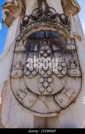 Un gros plan montre une sculpture en pierre d'un blason avec une couronne et des détails complexes, mettant en valeur des symboles héraldiques et du savoir-faire artisanal. Banque D'Images