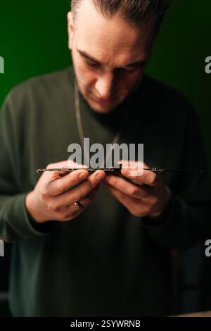 Portrait vertical du technicien concentré examinant attentivement la carte mère, dépannage des problèmes dans l'atelier de réparation électronique professionnel Banque D'Images