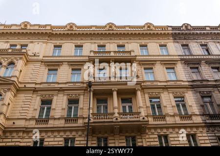 Un bâtiment historique de plusieurs étages avec une façade ornée, avec des moulures décoratives, des rangées de fenêtres et un balcon central avec des statues, se dresse agai Banque D'Images