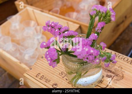 Fleurs violettes dans un petit bocal sur une caisse à vin en bois Banque D'Images
