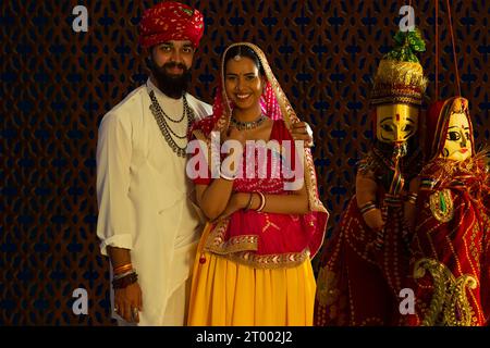 Portrait d'un couple Rajasthani avec des marionnettes au premier plan. Banque D'Images