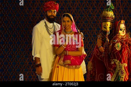 Portrait d'un couple Rajasthani avec des marionnettes au premier plan. Banque D'Images