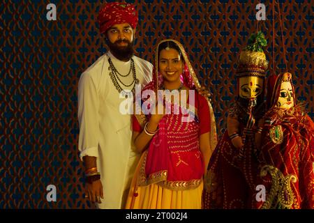 Portrait d'un couple Rajasthani avec des marionnettes au premier plan. Banque D'Images