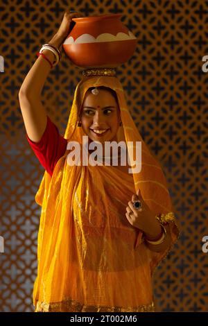 Une heureuse femme Rajasthani portant un pot d'argile sur sa tête Banque D'Images