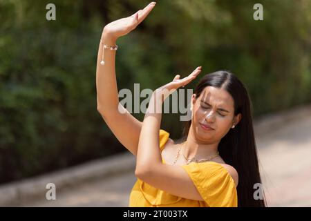 Femme couvrant son visage du soleil avec sa main dans le parc Banque D'Images