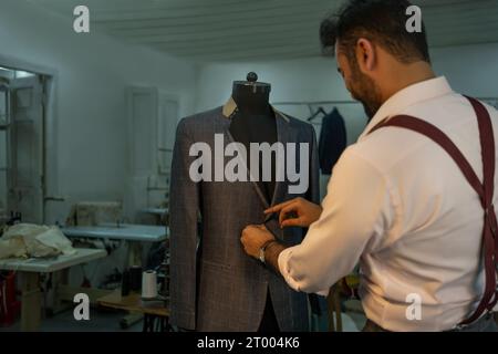 Un tailleur sur mesure vérifiant les mesures sur une forme de robe Banque D'Images