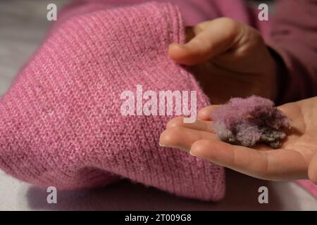 Femme utilisant le rasoir anti-boulochage à la maison. Dispositif pour raser des vêtements. Rasoir à tissu anti-peluche. Chandail portable électrique à pilule def Banque D'Images