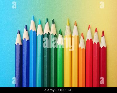 stylos colorés disposés dans les couleurs de l'arc-en-ciel sur papier coloré au cours de l'arc-en-ciel à la lumière du jour. crayons de bois multicolores brillants Banque D'Images