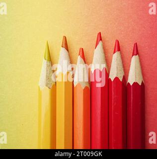 stylos colorés disposés dans les couleurs de l'arc-en-ciel sur papier coloré au cours de l'arc-en-ciel à la lumière du jour. crayons de bois multicolores brillants Banque D'Images