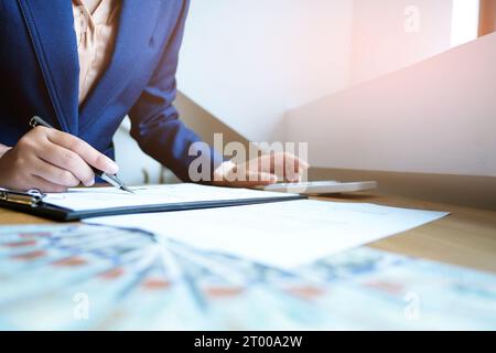 Homme d'affaires analysant les graphiques d'investissement et appuyant sur les boutons de la calculatrice au-dessus des documents.Concept comptable. Banque D'Images