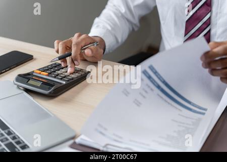 Homme d'affaires comptable analysant les graphiques d'investissement facture et appuyant sur les boutons de calculatrice sur les documents. Comptable comptable Banque D'Images