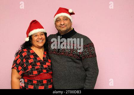 Couple latino avec le corps en surpoids positif portant des chapeaux de père noël sont heureux et excités à l'arrivée de décembre et célébrant Noël Banque D'Images