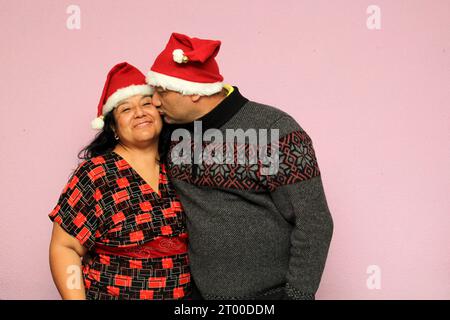Couple latino avec le corps en surpoids positif portant des chapeaux de père noël sont heureux et excités à l'arrivée de décembre et célébrant Noël Banque D'Images