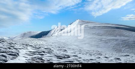 Crête de montagnes d'hiver avec chapeaux de neige en surplomb et pistes de snowboard sur fond de ciel bleu. Ukraine, Carpates, Svydovets rang Banque D'Images