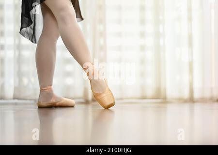 Cliché recadré de pieds de danseur de ballet dans des chaussures de pointe sur plancher en bois. Les gens, l'art de la danse, l'éducation et le concept de flexibilité Banque D'Images