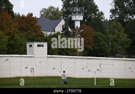 03 octobre 2023, Thuringe, Mödlareuth : mur et tour de guet le jour de l'unité allemande au Musée germano-allemand de Mödlareuth. Le village de Mödlareuth, où vivent environ 50 personnes aujourd'hui, est devenu internationalement célèbre comme «petit Berlin» après la Seconde Guerre mondiale. Les deux moitiés du village ont été séparées par la frontière, un mur divisait Mödlareuth. Photo : Martin Schutt/dpa Banque D'Images