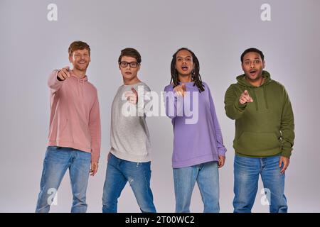 jeunes beaux hommes debout et pointant du doigt la caméra sur fond gris, diversité culturelle Banque D'Images