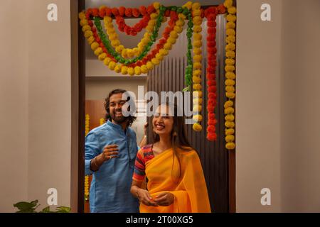 Portrait d'homme et de femme souriants debout à l'entrée pour accueillir leurs amis Banque D'Images