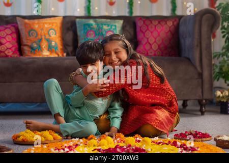 Frère et sœur s'amusant tout en décorant le sol avec des fleurs ( Rangoli) à l'occasion de Diwali Banque D'Images