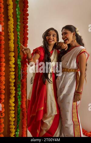 Portrait de deux sœurs bengali en tenue traditionnelle debout ensemble à la maison à l'occasion de Durga Puja Banque D'Images