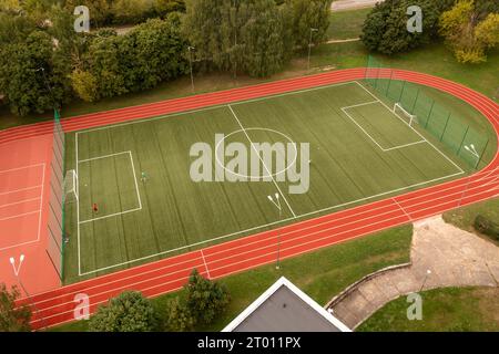 Drone photographie des enfants jouant au football dans un champ pendant la journée nuageuse d'été Banque D'Images