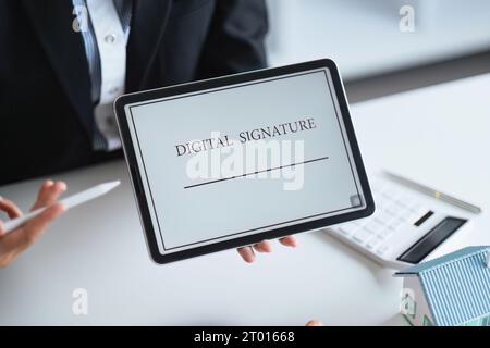 Gros plan d'un document électronique de signature de main féminine avec sur tablette. Signature électronique et concept de technologies modernes Banque D'Images