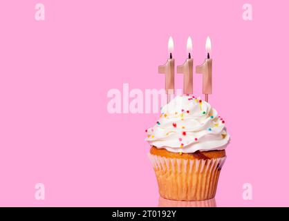 Gâteau d'anniversaire avec bougie numéro 111 - sur fond rose. Banque D'Images